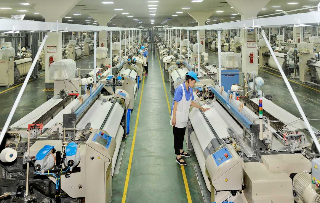 在棉织织造车间,挡车工正在精心操作.胡盼玲摄