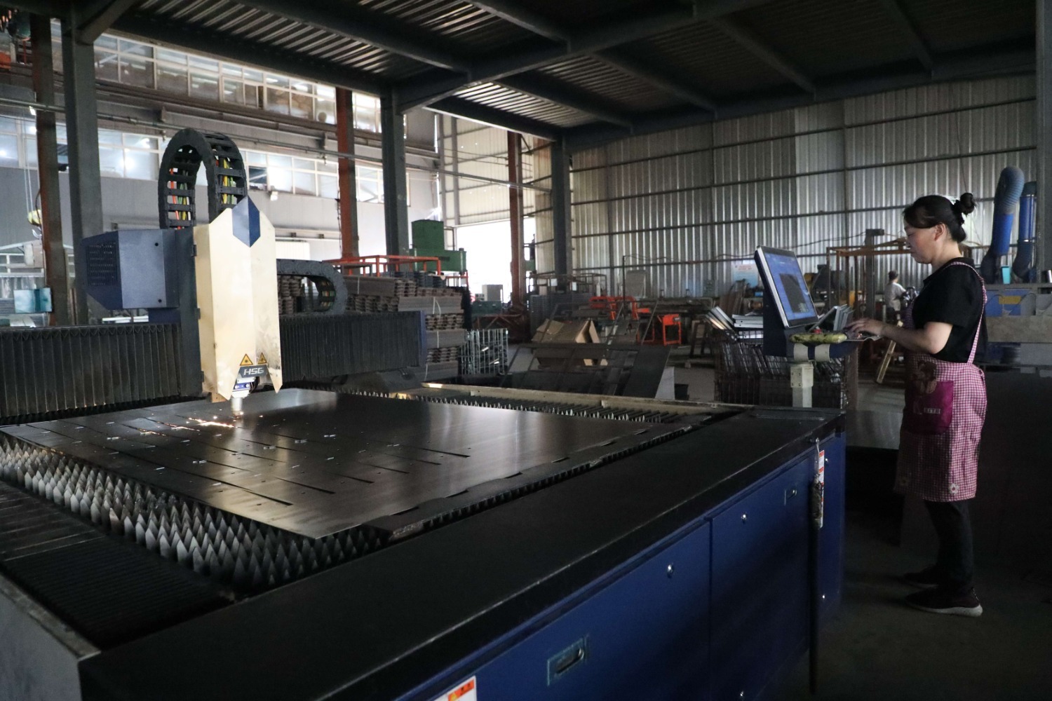 图为在香河强胜电动车制造有限公司生产车间,工人使用激光切割机进行