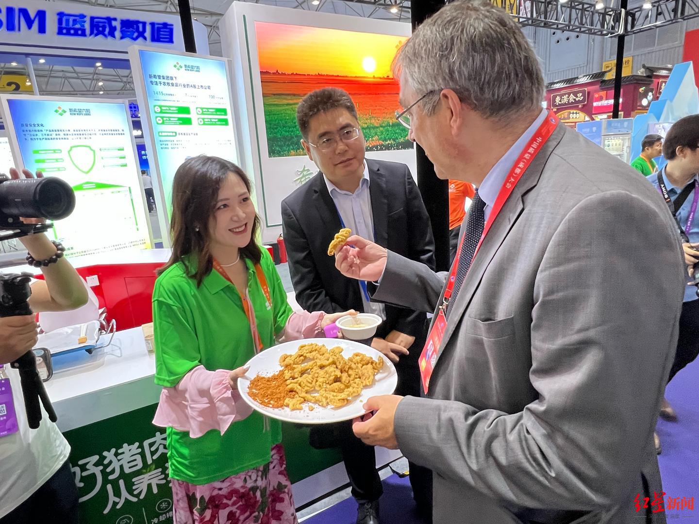 新希望六和食品产业总裁刘怀伟（中）向外宾推荐小酥肉