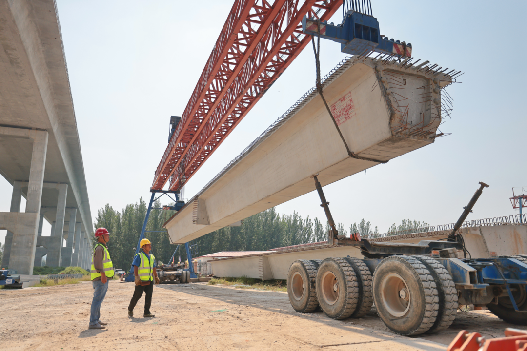 施工现场在运用设备吊运预制箱梁
