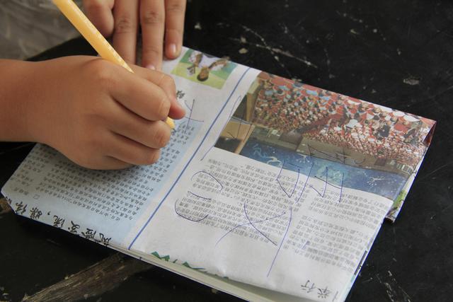 学生在展示利用废报纸包的书皮.图/ic photo