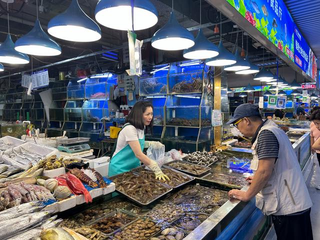 锦绣大地市场,摊主展示了改造完"生鲜灯"后,开灯关灯两种情况下,海鲜