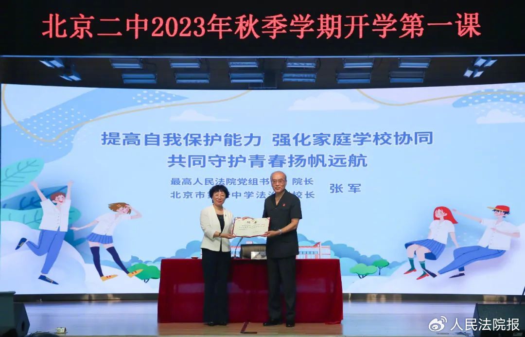 张军从北京二中校长薛丽霞手中接过法治副校长的聘书.