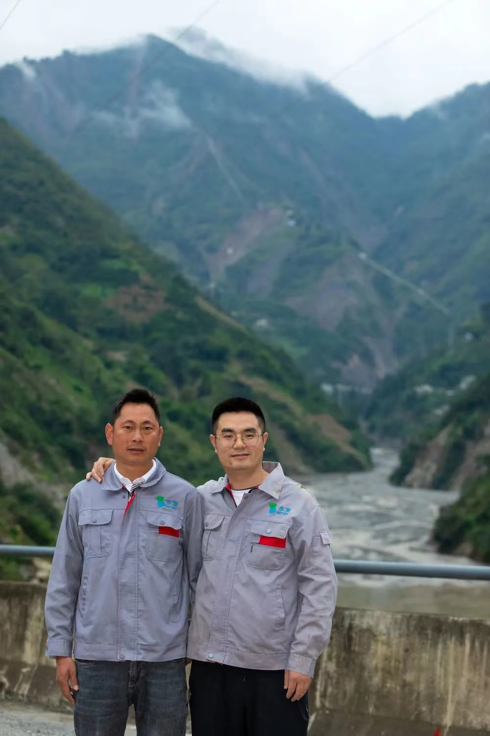 8月29日，甘宇（右）和罗永站在泸定县得妥镇联合村隧道外的大桥上，湾东水电站就建在他们身后的山谷里