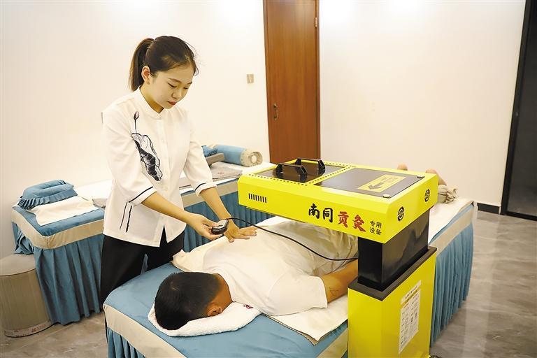 图为南京同仁堂贡灸养生馆廊坊店的理疗师为顾客做艾灸理疗.