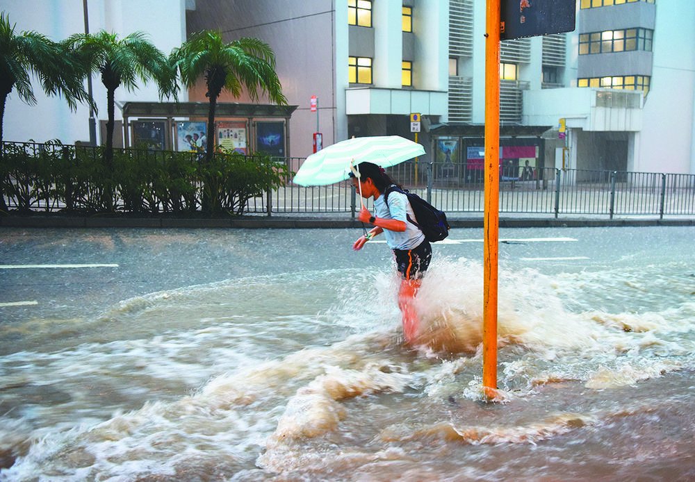 一名女士在香港皇后大道东路段涉水前行
