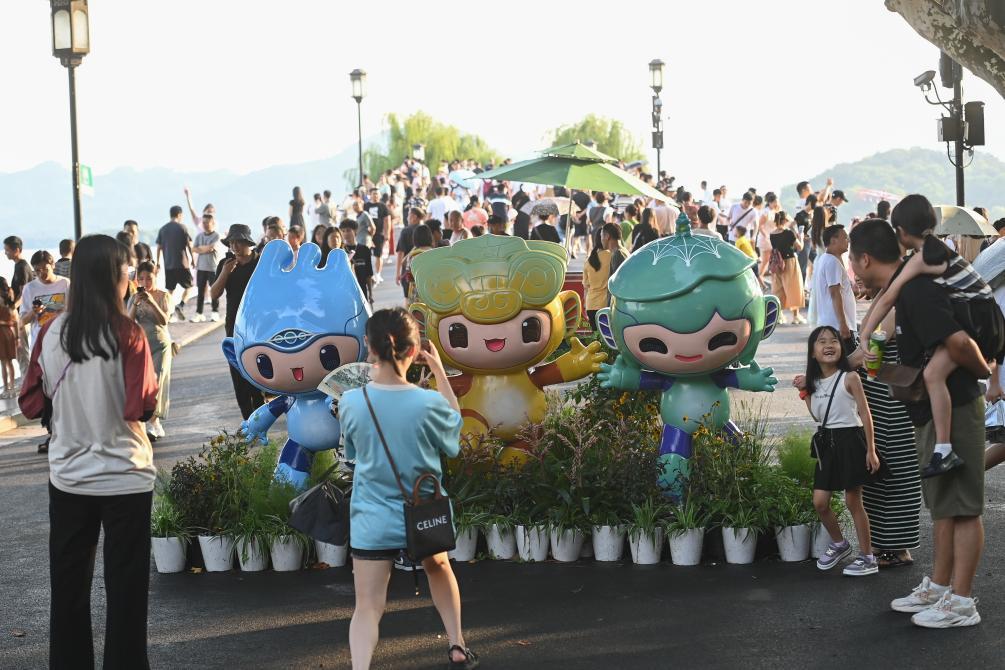 游客在位于杭州西湖景区的断桥边与杭州亚运会吉祥物合影。新华社记者黄宗治摄