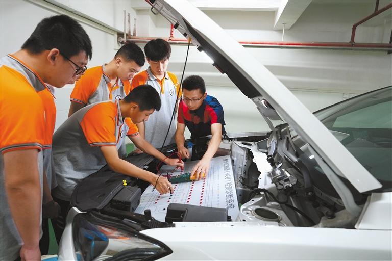 图为在重庆市北碚区职业教育中心新能源汽修实训室，教师（右一）在给学生讲解新能源汽车维修知识。 新华社发