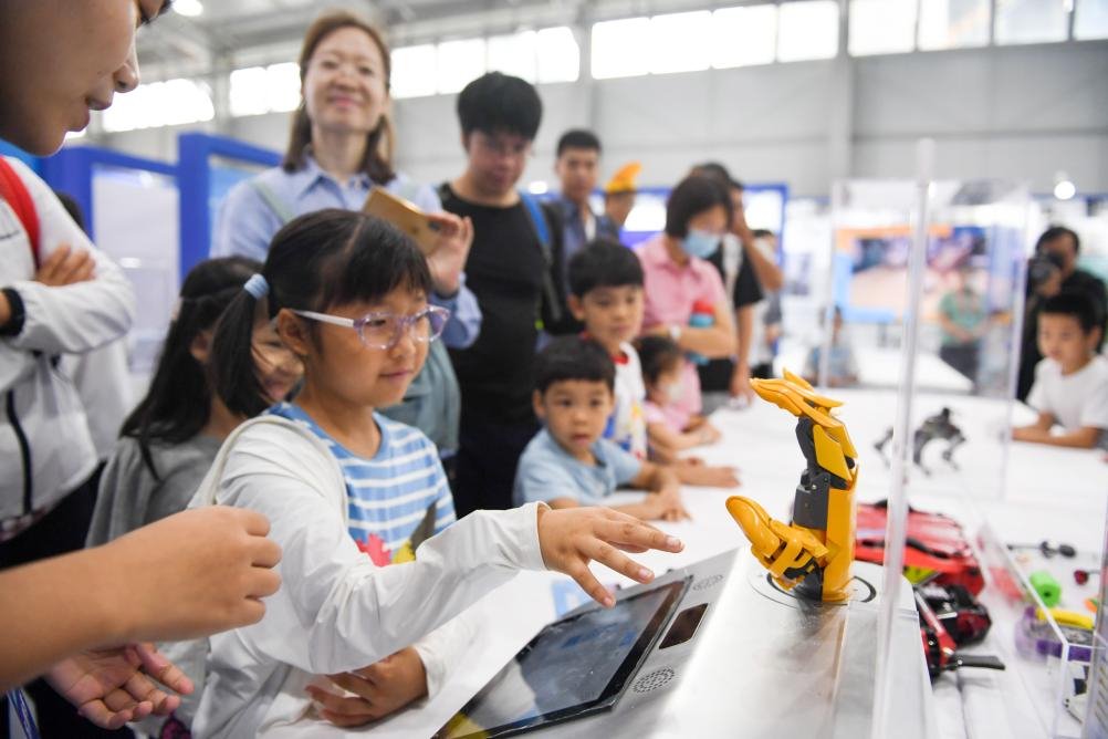 9月17日，在全国科普日北京主场活动展区，小朋友体验与一款机器手进行动作同步。新华社记者鞠焕宗 摄