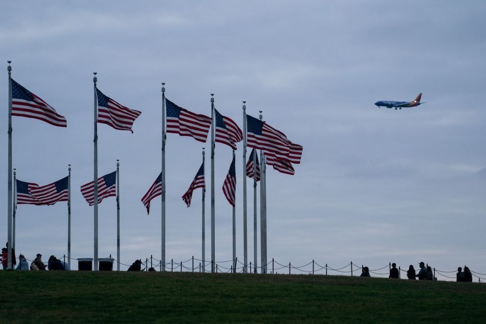 2022年11月10日，在美国首都华盛顿，一架飞机从美国国旗上空飞过。新华社记者刘杰摄