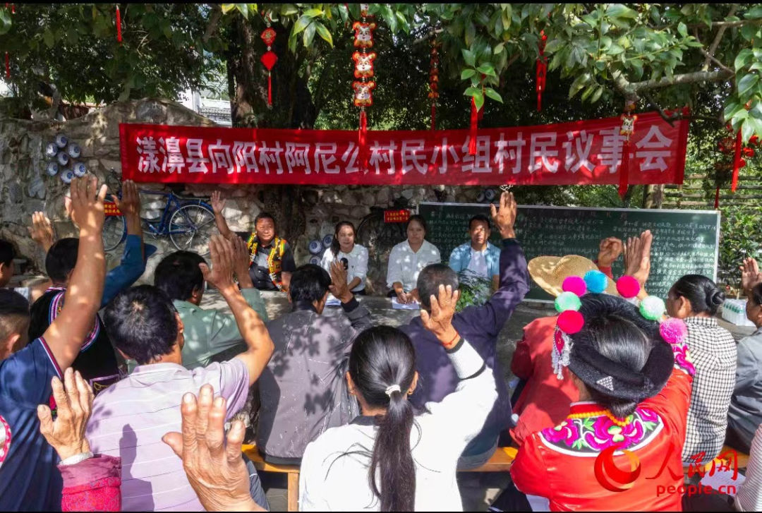 图为村民举手表决通过了《阿尼么村民小组村规民约》.人民网 周静圆摄