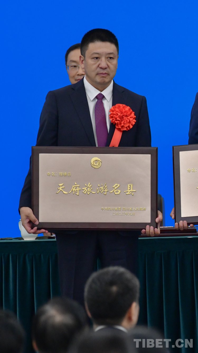 图为理塘县委书记董德洪领取天府旅游名县牌匾