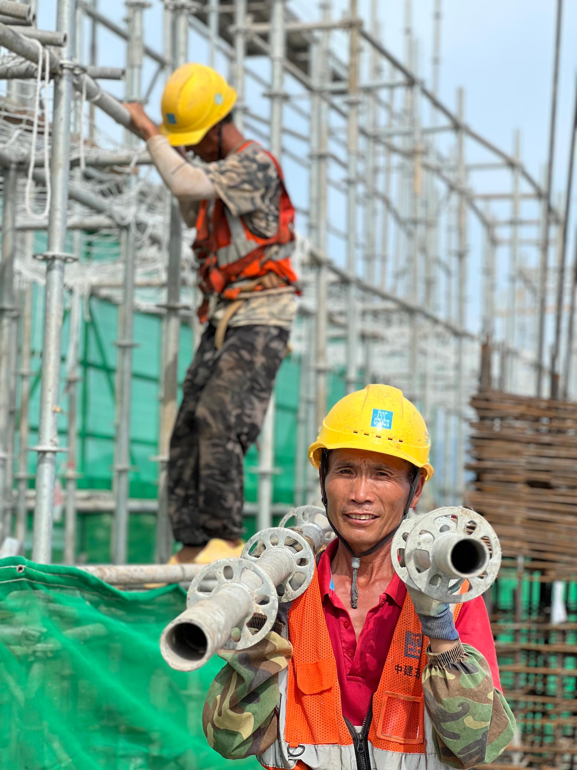 脚手架班组工人在主楼二层搬运材料 .