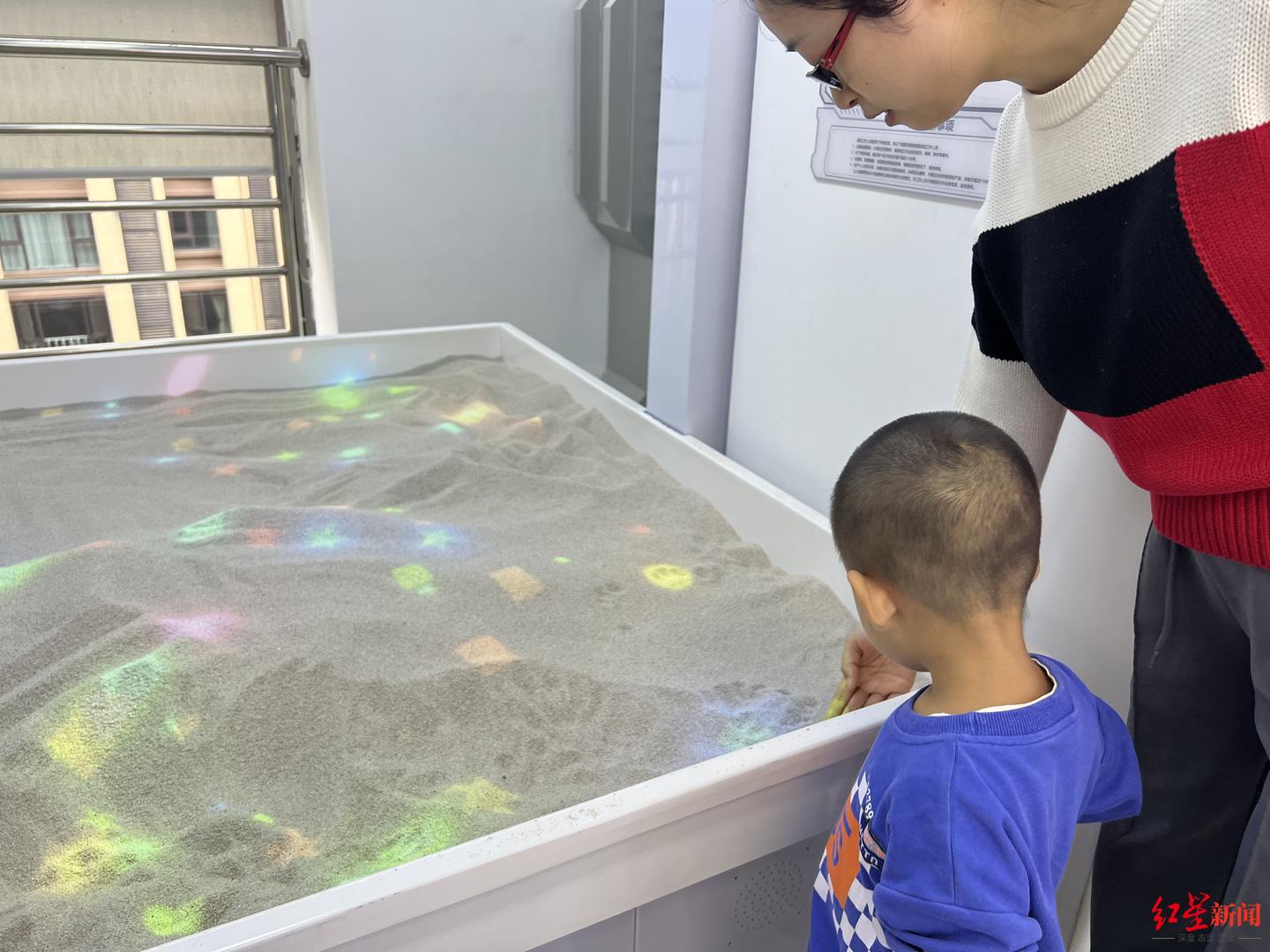 ▲在VR互动沙盘区域，吴女士正带着两岁半的儿子进行项目体验