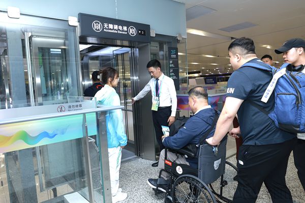 机场工作人员引领运动员乘坐无障碍电梯(杭州机场供图)