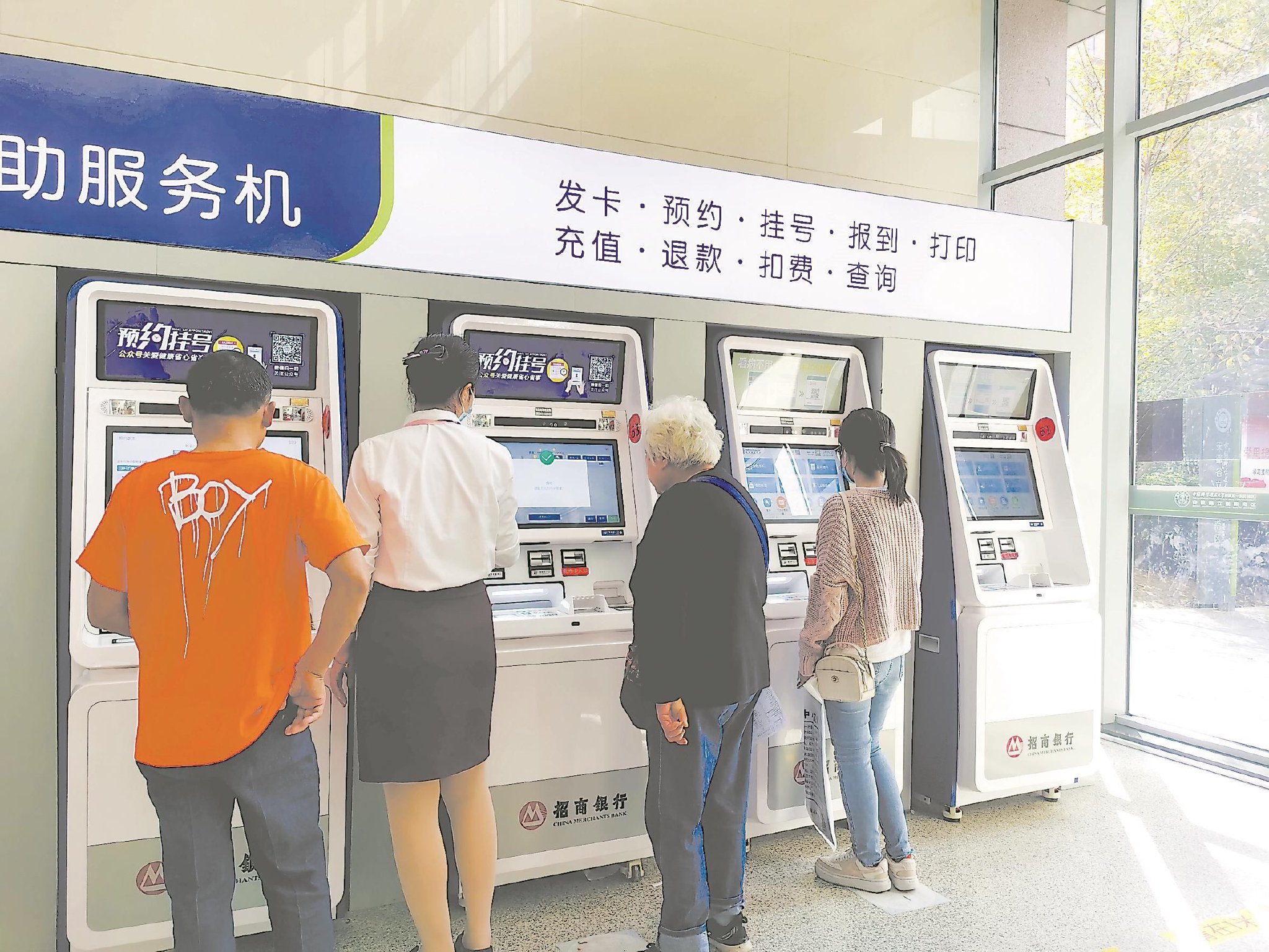 第一附属医院南区,一名老人在导医帮助下使用自助挂号机打印检查结果