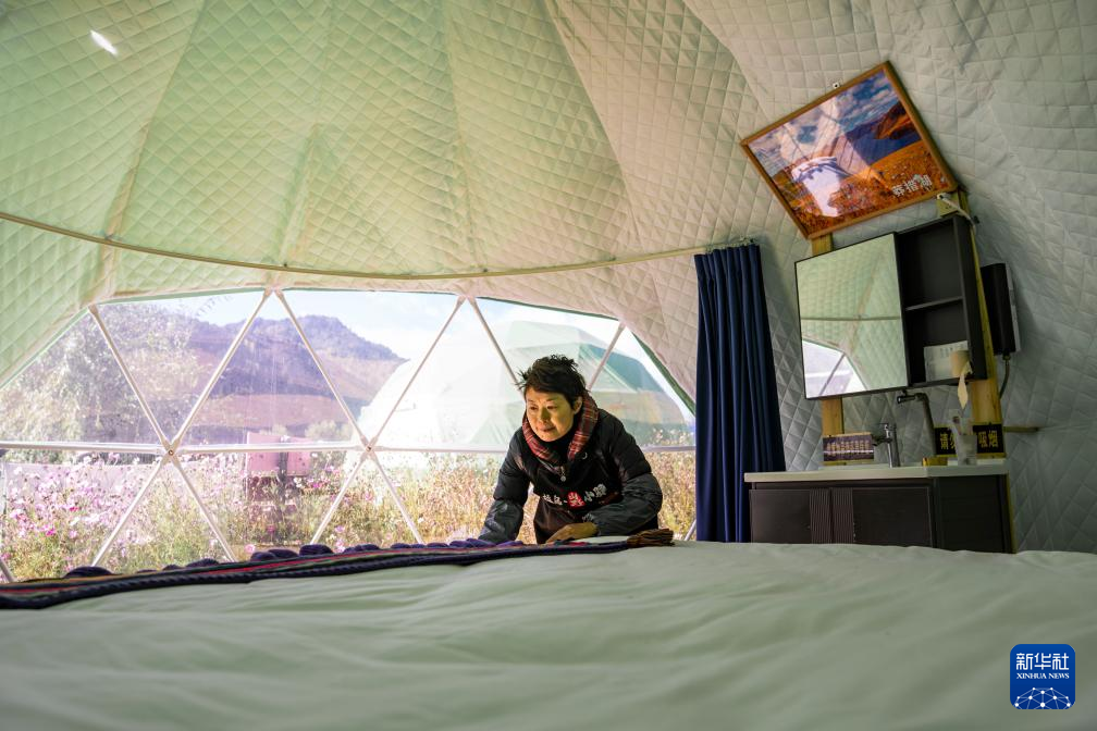 工作人员在西藏芒康县如美镇拉乌村一座星空帐篷内收拾床铺(10月20日