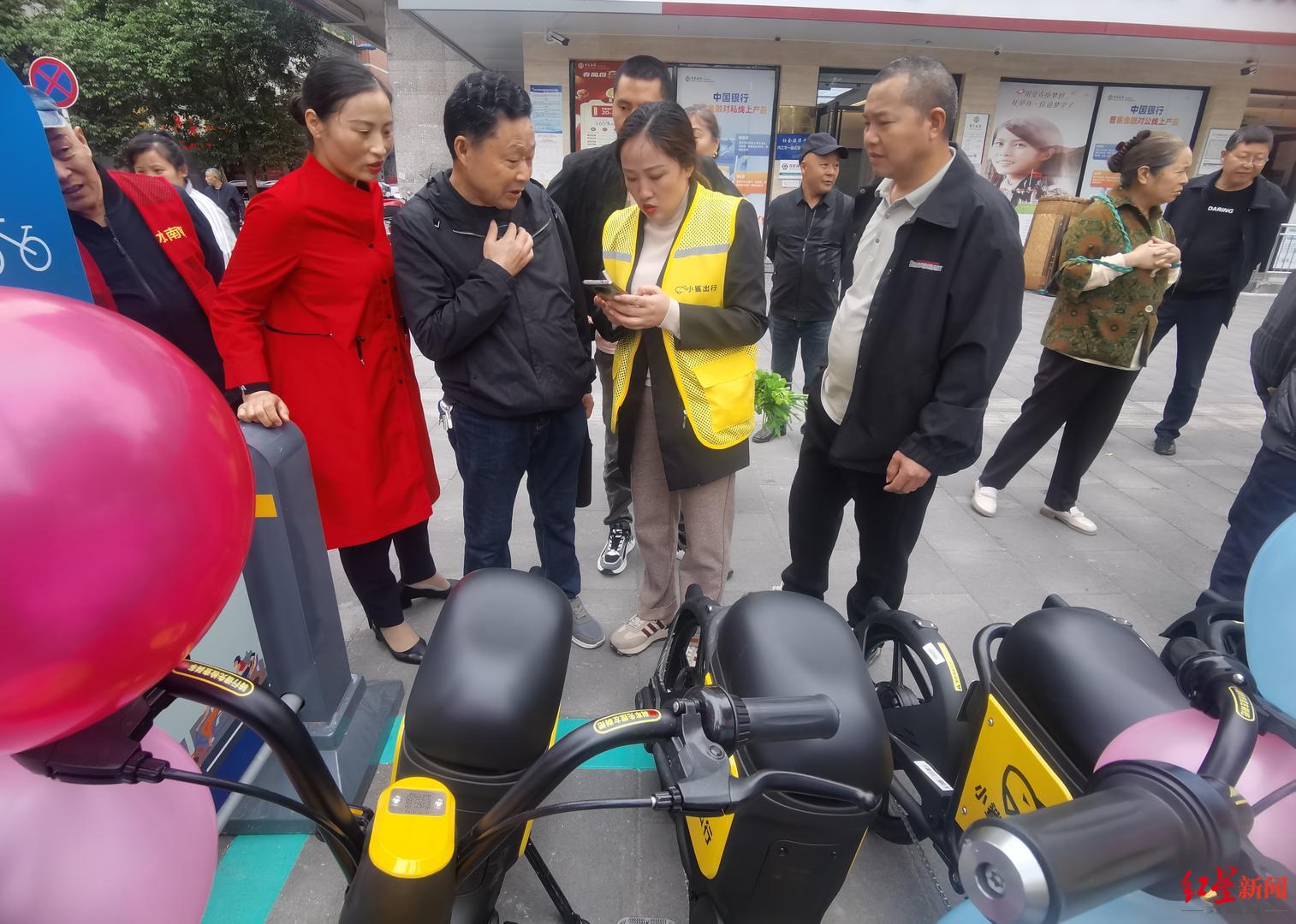 ▲共享电单车企业工作人员指导扫码骑行