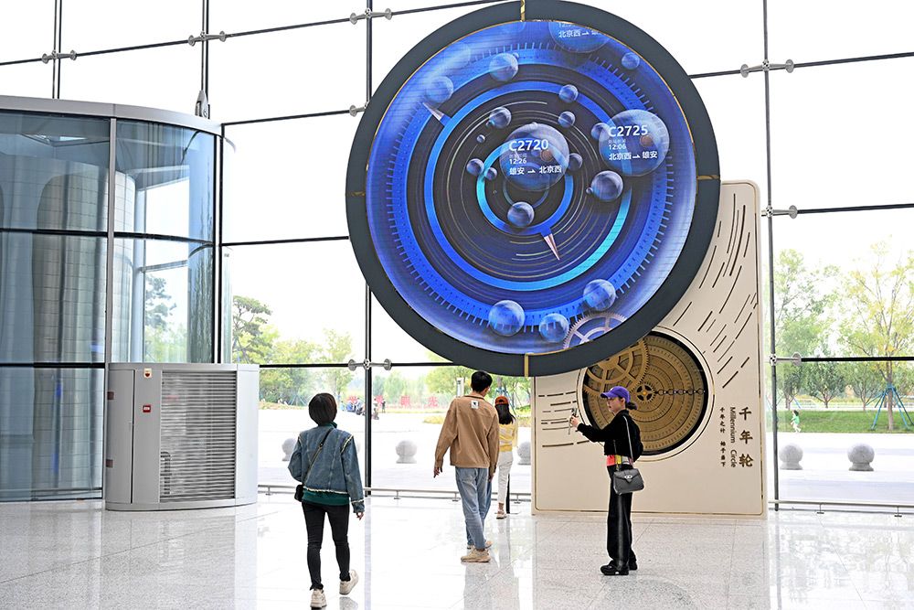 乘客在雄安站"千年轮"前拍照留念.河北日报记者 张昊摄