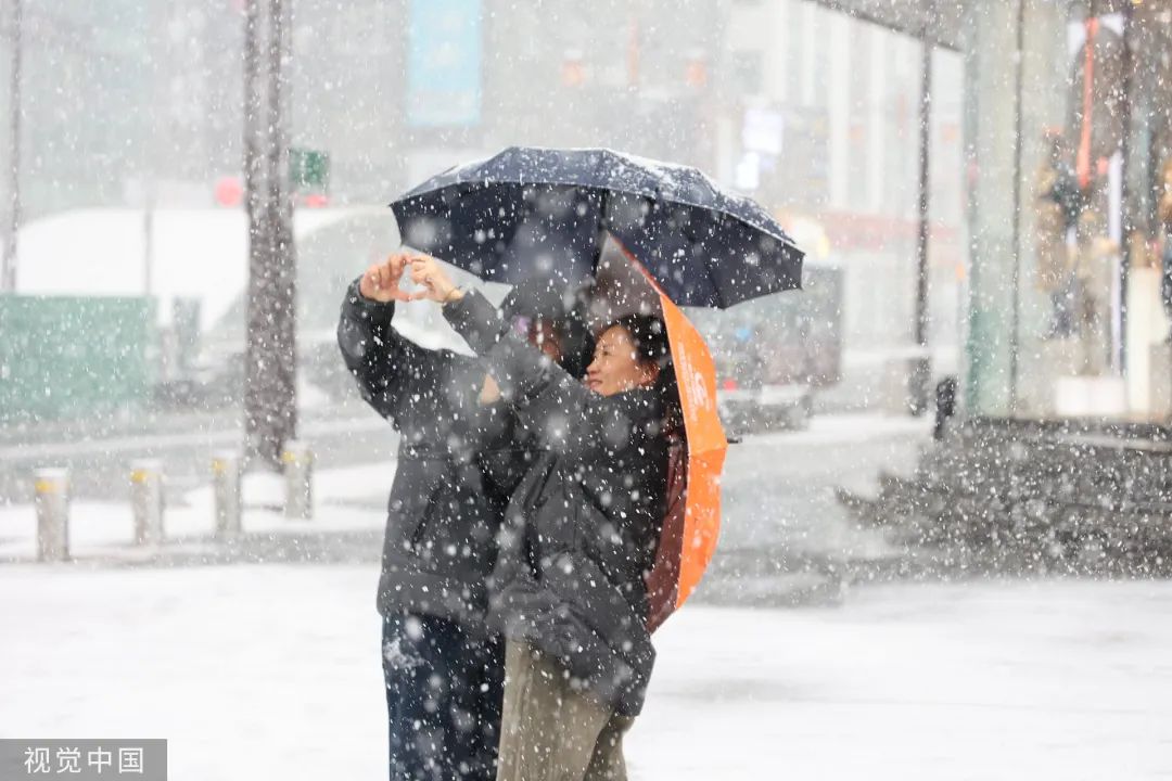 2023年11月6日,沈阳中街步行街,市民在雪中出行
