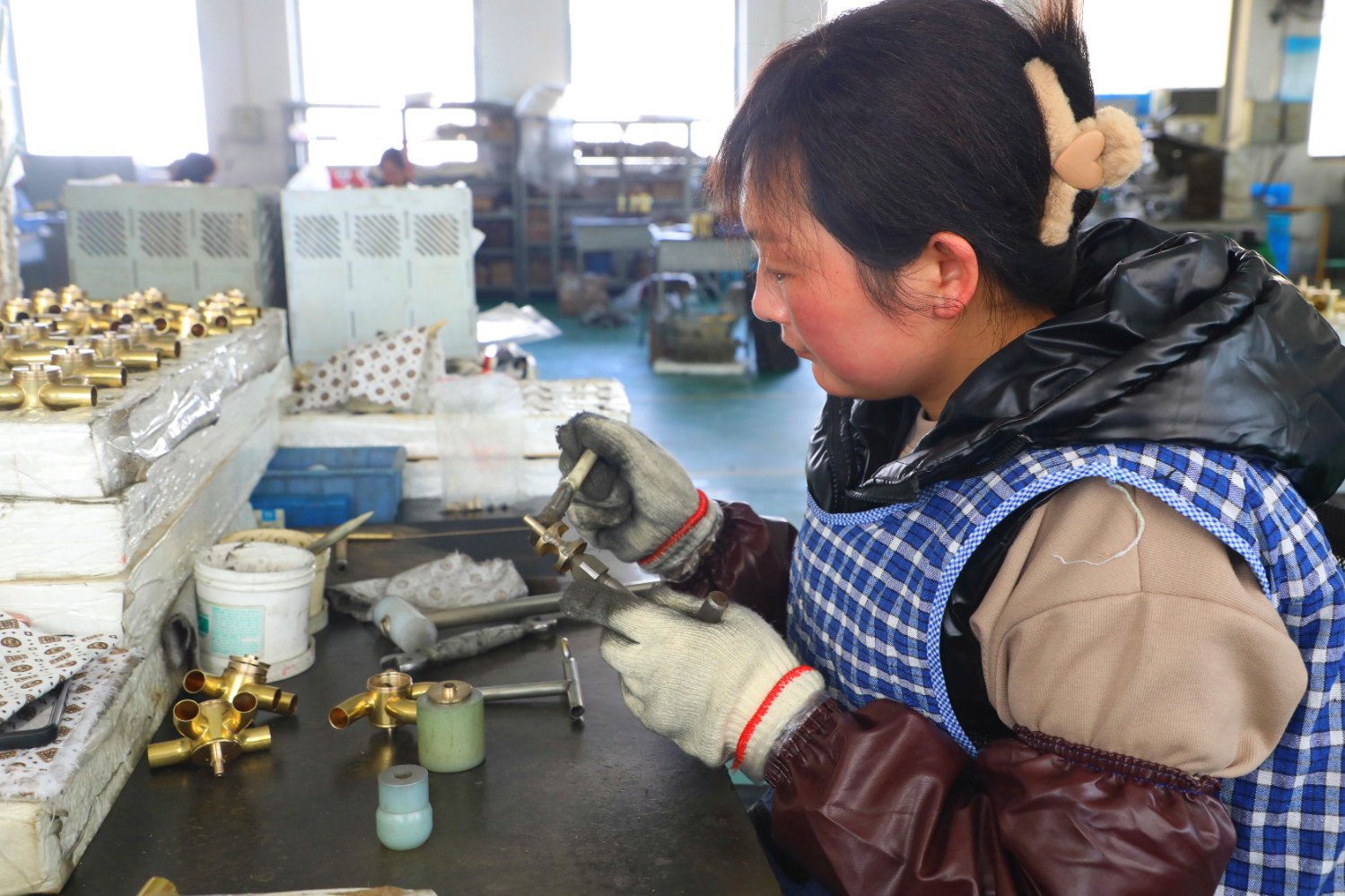 图为在伊斯曼乐器有限公司生产车间,工人正在手工制作旋转活塞.