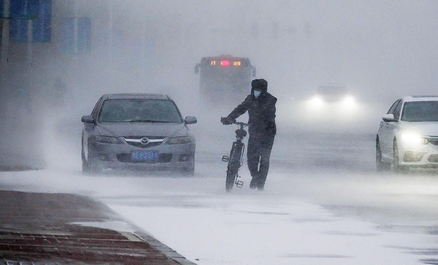 黑龙江大庆,受大风加雪的影响,路上的车辆和行人在风雪中艰难前行,为