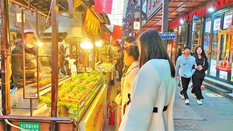 兰州市城关区大众巷的新光夜市人头攒动,来往的市民拿出手机在街区特