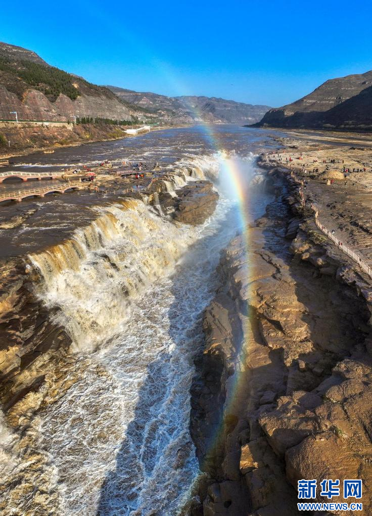 11月16日,黄河壶口瀑布底部的水潭波光粼粼,一道彩虹飞架在瀑布上空