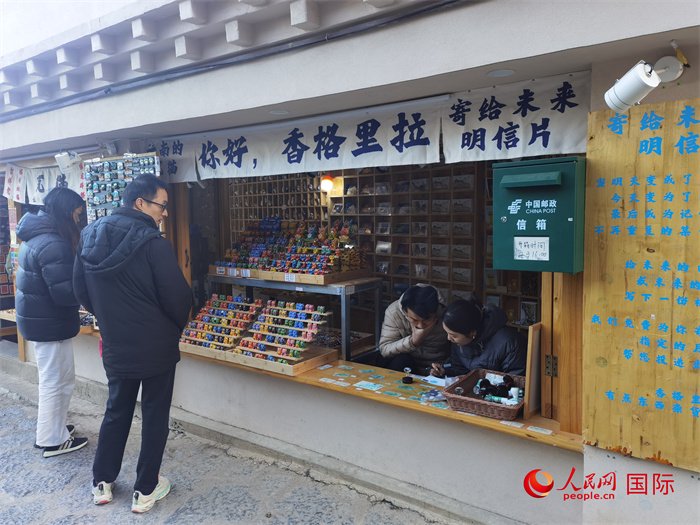 游客在独克宗古城景区写明信片寄给未来的自己.人民网记者杜明明摄