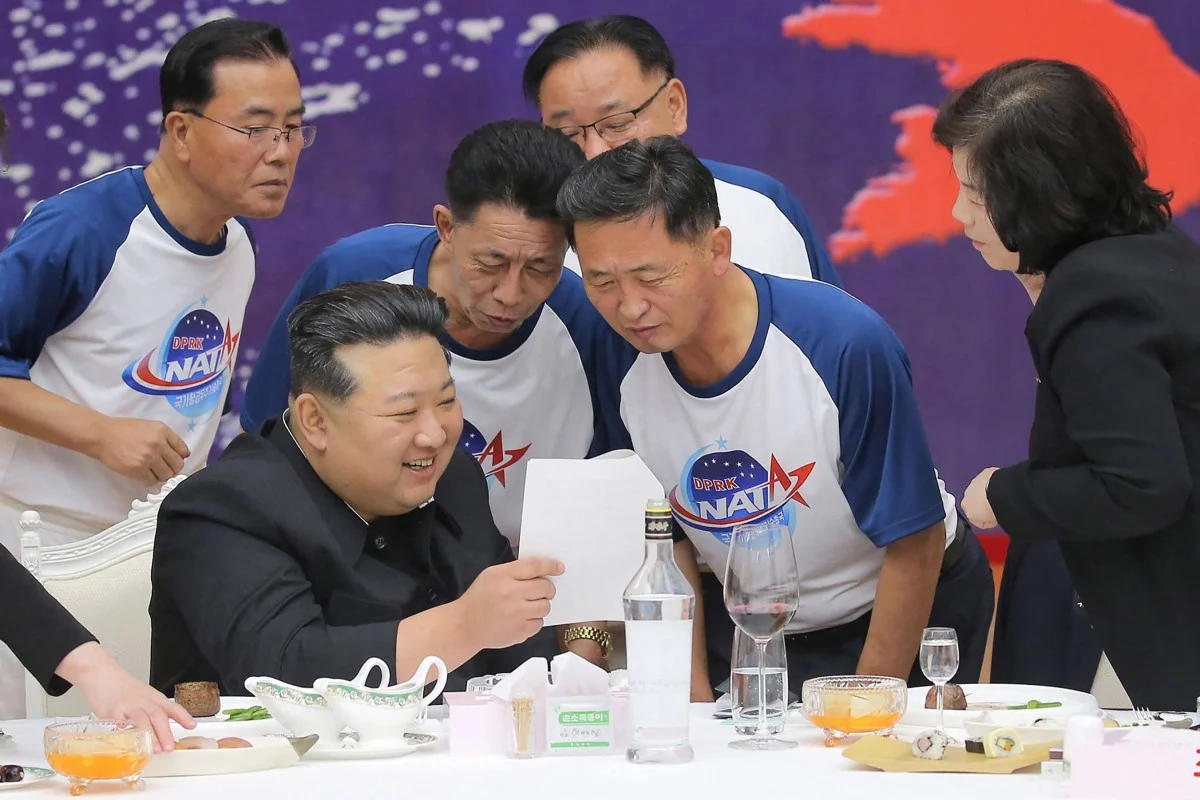 ▲朝鲜领导人金正恩在庆祝侦察卫星发射的宴会上与该国航天局官员互动