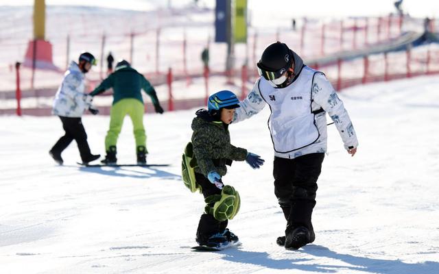 12月1日，北京渔阳国际滑雪场，滑雪教练正在教小朋友单板滑雪。 新京报记者 王贵彬 摄