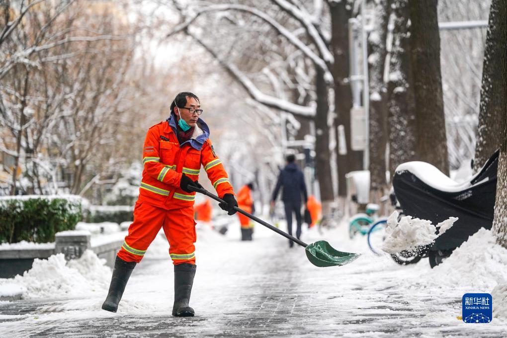 12月11日,环卫工人在雪后的北京前门西大街清理人行道上的积雪.
