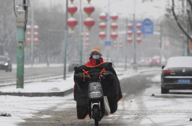 12月13日上午，延庆飘起鹅毛大雪，市民在雪中骑电动车。新京报记者 王颖 摄