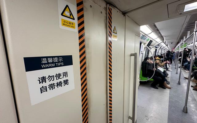 地铁14号线,车厢连接处贴有"请勿使用自带椅凳"提醒.