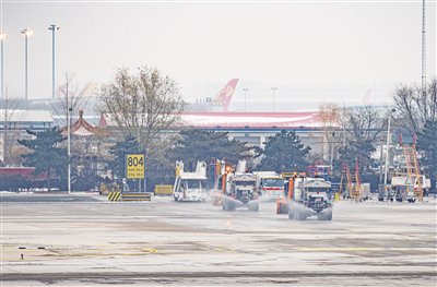 12月13日，北京首都国际机场，机场除雪车正在机坪上撒融雪剂。新京报记者 陶冉 摄