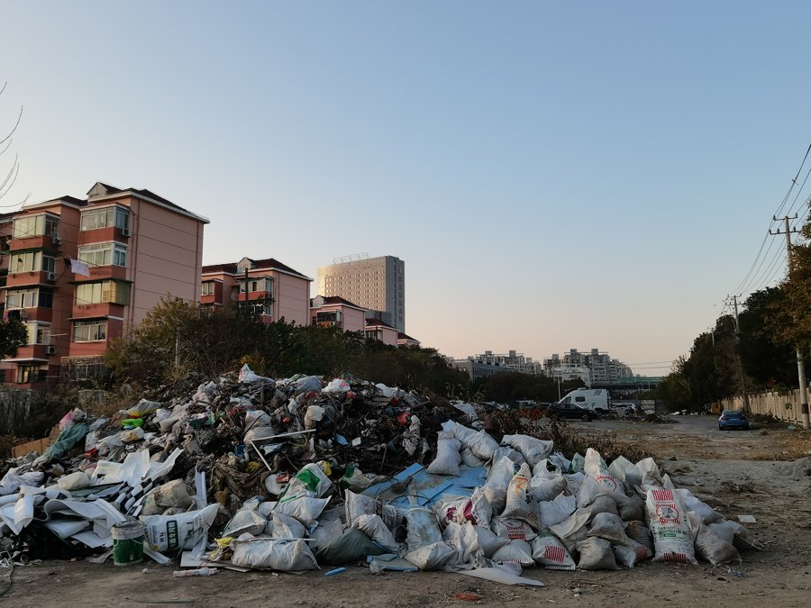 停车场内堆放着大量建筑垃圾,汽车在"垃圾山"间停放.