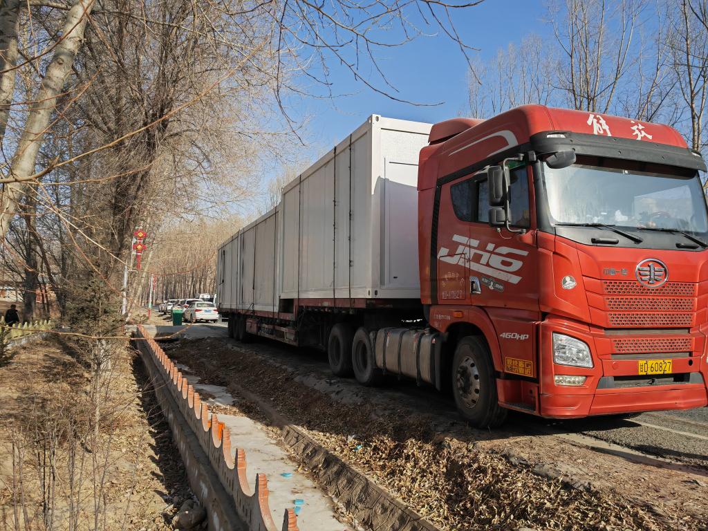 装着集装箱式彩钢板房的物资车运抵积石山县刘集乡陶家村.