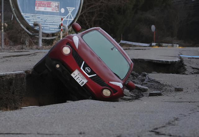 当地时间2024年1月2日，日本石川县水津镇，一辆汽车倒在裂缝的道路上。图自视觉中国