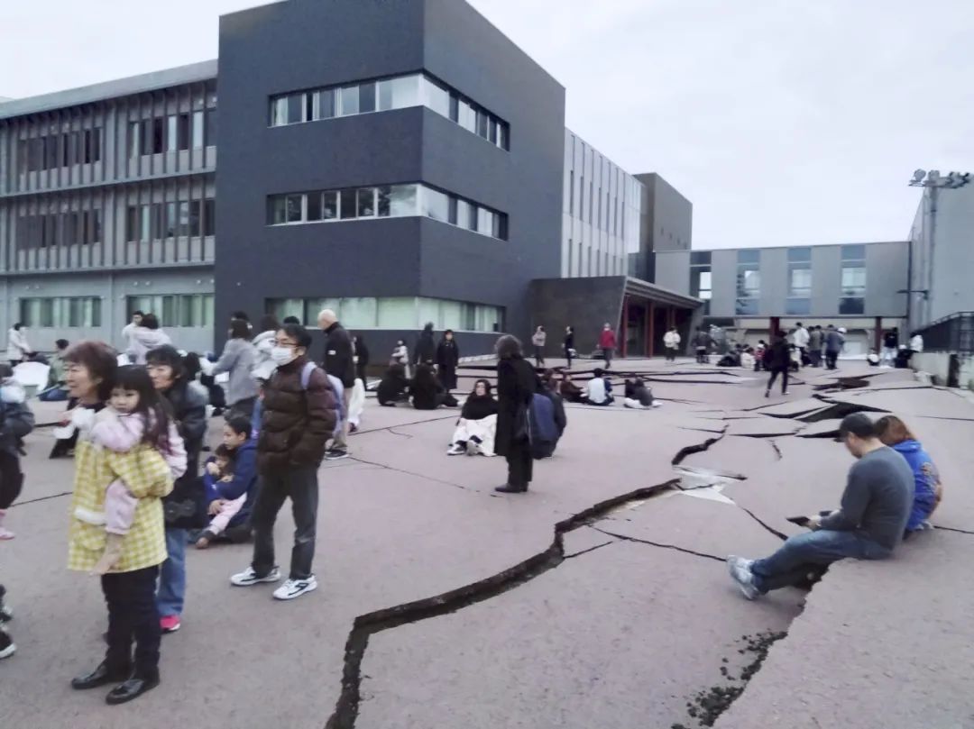 1月1日，在日本石川县轮岛市，人们站在被地震破坏的地面上。图片来源：新华社/共同社