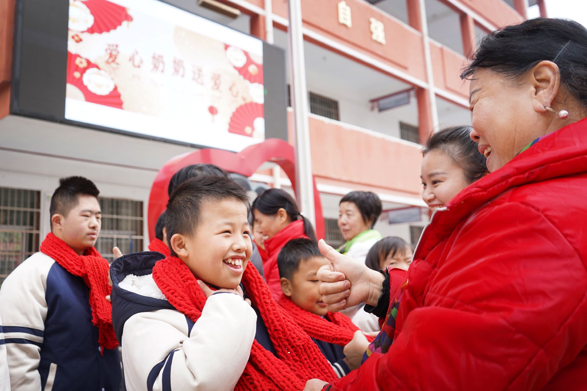 志愿者和"爱心奶奶"为特殊学校的孩子们佩戴编织的围巾 陈旗海 摄