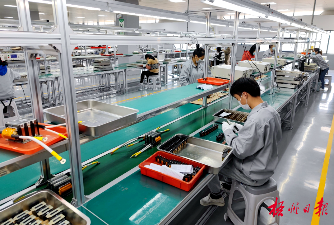 科技有限公司新能源汽车电子设备生产车间的工人正在忙碌装配电子配件