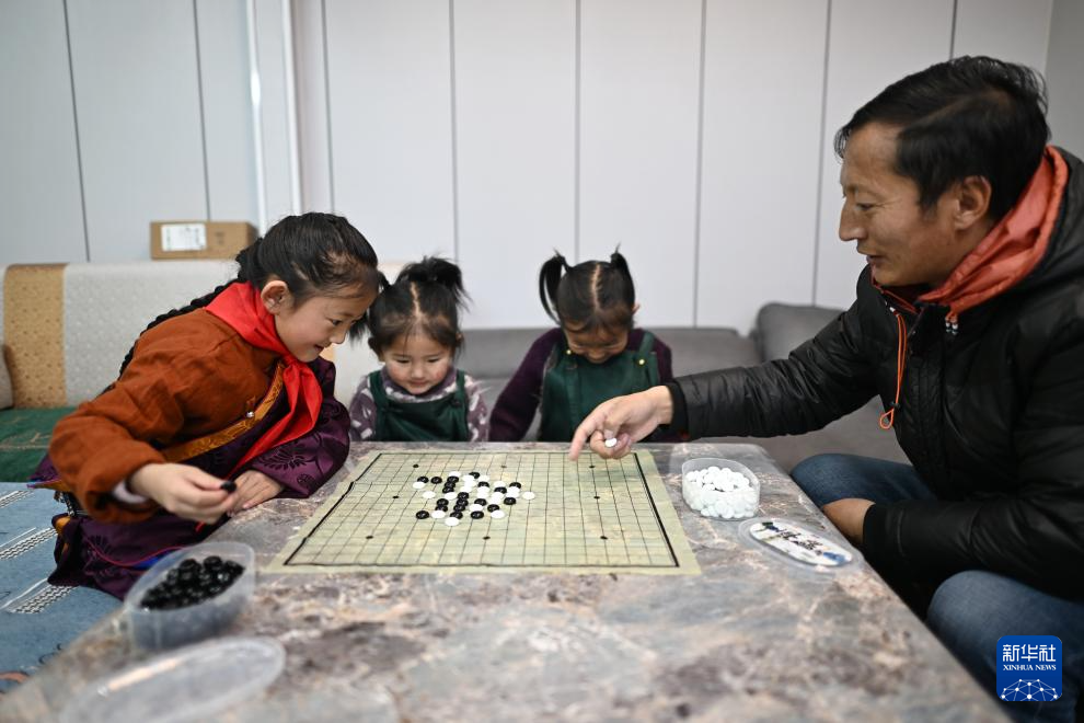 青海玉树曲麻莱县第二民族完全小学学生达沙旦增德金（左一）在家中和爸爸一起下五子棋（1月12日摄）。新华社记者 张宏祥 摄