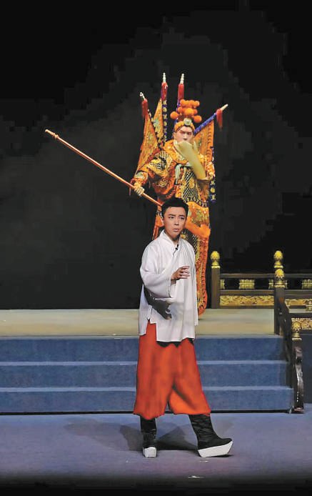 谭正岩在舞台上演出,舞台后方是以传统京剧《定军山》中经典造型