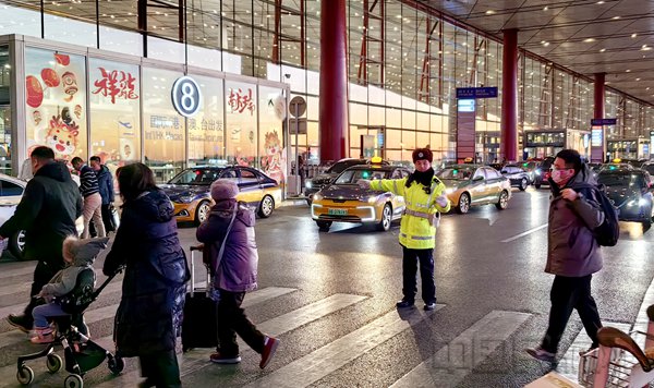 首都机场公安局北京首都国际机场分局交通警察支队民警在航站楼前疏导早高峰车辆和旅客