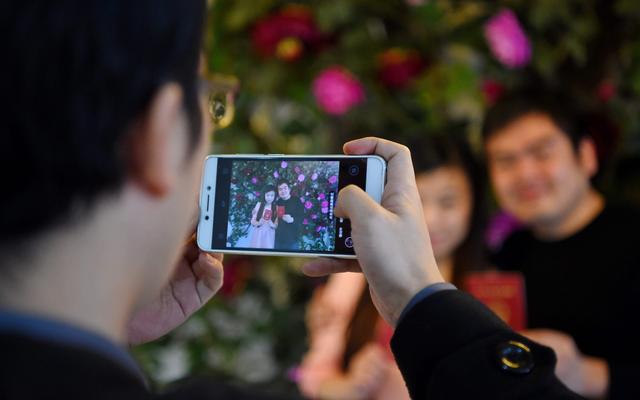 资料图:在辽宁沈阳市皇姑区民政局婚姻登记处,两位新人手持结婚证