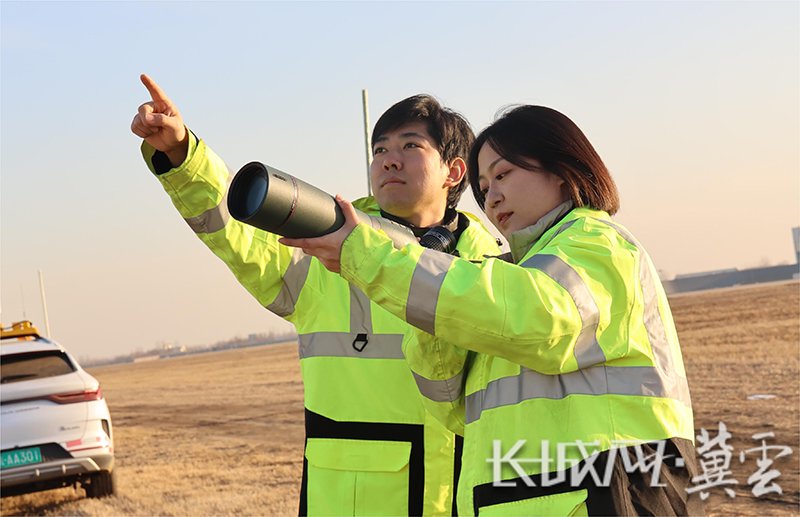 刘艺凯教记者使用望远镜观察鸟类飞行情况.