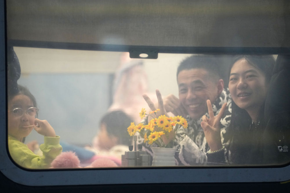 1月26日，在哈尔滨火车站，旅客在列车上向窗外比手势。新华社记者 王建威 摄