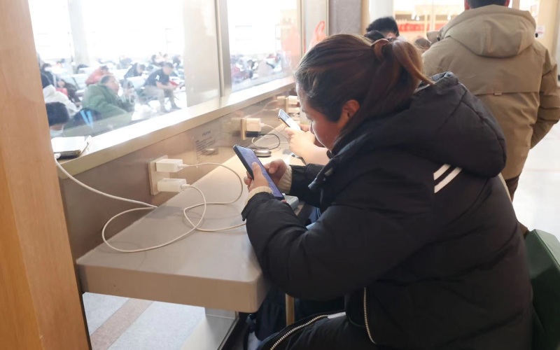 旅客坐在自助服务区内为手机充电。新京报记者 王贵彬 摄