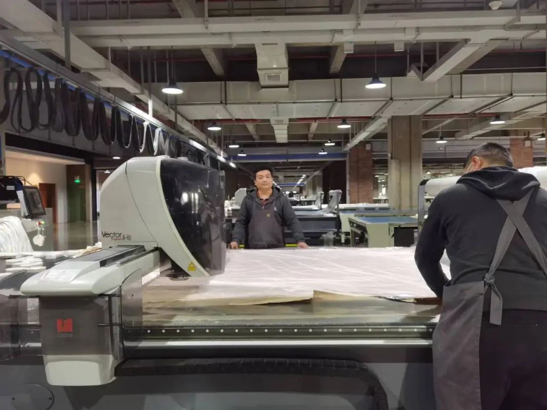 在童泰服装的裁剪车间,国际先进裁床正在自动剪裁面料.