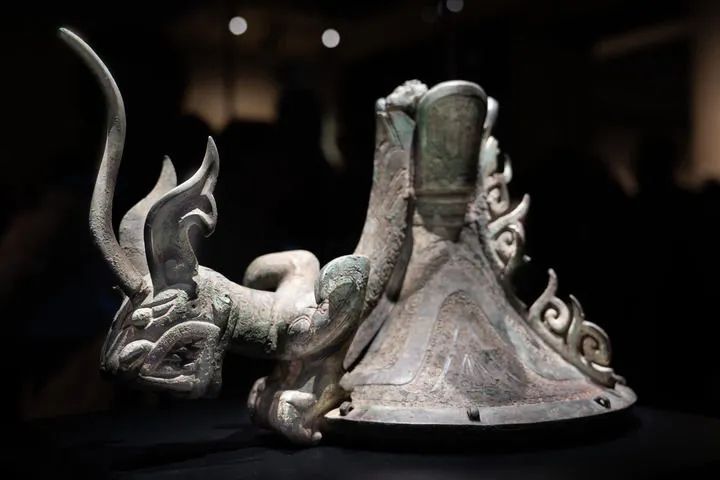 三星堆青铜鸟足神像的朱砂彩绘觚形尊上有一爬龙器盖,龙俯身在青铜立